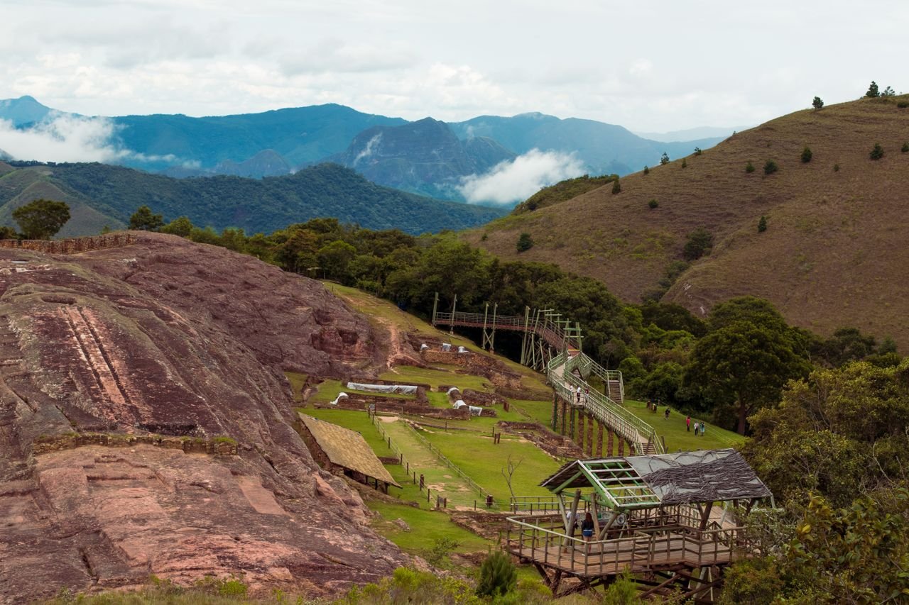 A scenic view of the Samaipata archaeological site amidst lush hills and clouds.